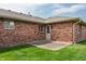 Exterior view of the backyard of a red brick house with a small concrete patio at 126 Appian Way, Anderson, IN 46013