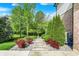 Landscaped walkway leading to a brick home with colorful plants and green trees at 13934 Salsbury Creek Dr, Carmel, IN 46032