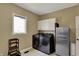 Well-lit laundry room featuring black washer/dryer set, stainless steel fridge, and white cabinetry for ample storage at 13934 Salsbury Creek Dr, Carmel, IN 46032