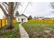Spacious backyard with grass, mature trees, wooden fence, and the house with a red door at 1451 N Grant Ave, Indianapolis, IN 46201
