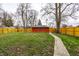 Large backyard with grass, mature trees, wooden fence, and a red detached garage at 1451 N Grant Ave, Indianapolis, IN 46201