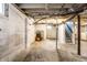 Unfinished basement featuring concrete walls, support beam, and access to the laundry area at 1451 N Grant Ave, Indianapolis, IN 46201