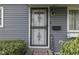 Close-up of the front door with secure screen, gray siding, and a 'Welcome' sign at 1643 E Tabor St, Indianapolis, IN 46203