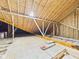 An unfinished attic space with exposed beams and plywood flooring, offering potential for customization at 2327 Mimosa Ln, Anderson, IN 46011