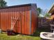 Side view of outdoor shed featuring wood siding, a white door, and surrounding green lawn at 2630 Wedgewood Dr, Columbus, IN 47203