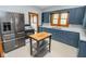 An updated kitchen offers sleek, stainless steel appliances, ample counter space, and stylish blue cabinets at 300 E 2Nd St, Sheridan, IN 46069