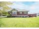 View of the back of this home with a large manicured lawn and wooden stairs leading to the back door at 300 E 2Nd St, Sheridan, IN 46069