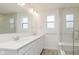 Bathroom featuring dual sinks, quartz countertop, and a glass enclosed shower with tiled walls and bench seat at 3305 Noriker Ln, Zionsville, IN 46077
