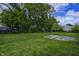 Spacious backyard with mature trees, grassy lawn, and partial concrete pad at 3549 N Sherman Dr, Indianapolis, IN 46218