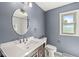 Neutral bathroom featuring toilet, mirror, sink, and window at 4152 S Creekside Dr, New Palestine, IN 46163