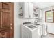 Bright laundry room features white cabinetry, modern washer and dryer, and dark wood door at 4152 S Creekside Dr, New Palestine, IN 46163