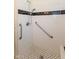 Tile shower with handrails and black and white patterned floor at 4710 Hinesley Ave, Indianapolis, IN 46208