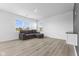 Bright living room with modern flooring, large windows, and a gray sofa in a minimalist design at 4985 W Burrel Ln, New Palestine, IN 46163