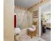 Cozy full bathroom features a shower-tub combo, and decorative floral wallpaper in an adjacent bedroom at 5615 Burning Tree Ct, Indianapolis, IN 46239