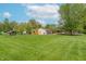 Expansive backyard view featuring a well-maintained lawn, storage sheds, and mature trees at 5901 W Thompson Rd, Indianapolis, IN 46221