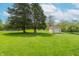 Beautiful backyard showcasing a storage shed surrounded by lush green grass and mature trees at 5901 W Thompson Rd, Indianapolis, IN 46221