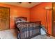 Bedroom with orange walls. Hardwood doors and a ceiling fan make this the perfect space to relax at 5901 W Thompson Rd, Indianapolis, IN 46221