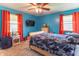 Bright bedroom with blue walls, orange curtains, and ceiling fan. Natural light comes in from the side windows at 5901 W Thompson Rd, Indianapolis, IN 46221