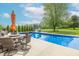 Backyard pool area featuring a dining set, slide, and lush landscaping, perfect for summer entertaining at 5901 W Thompson Rd, Indianapolis, IN 46221
