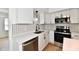 Modern kitchen with stainless steel appliances, white cabinets, and monochrome backsplash at 609 Delray Dr, Indianapolis, IN 46241