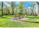 Backyard fire pit with benches surrounded by green grass and mature trees creating a peaceful outdoor space at 6149 W Olive Branch Rd, Greenwood, IN 46143