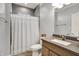 A well-lit bathroom featuring gray tile, a shower with a curtain, and a vanity with a speckled countertop at 6149 W Olive Branch Rd, Greenwood, IN 46143