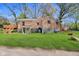 Exterior backyard view of brick home with lush green grass and deck area, offering outdoor space at 7002 N Ralston Ave, Indianapolis, IN 46220