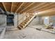 Unfinished basement with concrete floors, block walls, exposed wood ceiling beams, and access stairs at 7002 N Ralston Ave, Indianapolis, IN 46220