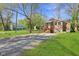 Inviting brick home with a covered front porch, surrounded by lush greenery and a stone driveway at 7002 N Ralston Ave, Indianapolis, IN 46220