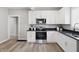 Bright kitchen features white cabinets, stainless steel appliances, black countertops, and wood-look floors at 717 S A St, Elwood, IN 46036