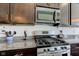Close up of a modern kitchen with stainless steel gas range, microwave, granite countertops, and dark cabinets at 745 S Summerhaven Ct, New Palestine, IN 46163