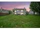 Backyard view features lush green grass, patio, hot tub, and outdoor seating area at dusk at 8875 White Fir Dr, Indianapolis, IN 46256