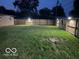 Nighttime view of the backyard with a wooden fence and illuminated surroundings at 9748 W Sunset Ln, Elwood, IN 46036