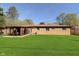 Back exterior view displaying a sunroom, grassy yard, and brick home features at 9748 W Sunset Ln, Elwood, IN 46036