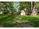 View of detached garage in backyard with mature tree coverage and grass lawn at 112 Coronado Rd, Indianapolis, IN 46234