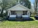 Charming one-story home with a covered porch, front lawn, and mature trees at 1221 E 22Nd St, Anderson, IN 46016