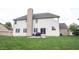 Back exterior with vinyl siding, a stone chimney, a patio, and green grass at 12493 Loudoun Pl, Fishers, IN 46037
