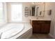 Bright bathroom featuring a soaking tub, a window bringing in natural light, and vanity with dark wood cabinets at 12493 Loudoun Pl, Fishers, IN 46037
