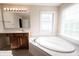 Bright bathroom featuring a soaking tub, a window bringing in natural light, and vanity with a large mirror at 12493 Loudoun Pl, Fishers, IN 46037