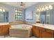 Relaxing bathroom featuring a corner soaking tub with wood cabinets and ample counter space at 12608 E 86Th St, Indianapolis, IN 46236