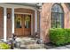 Charming brick home facade with a double-door entryway adorned with wreaths, enhanced by stone steps and mature greenery at 12608 E 86Th St, Indianapolis, IN 46236