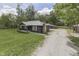 Charming one-story home with stone chimney and dark siding surrounded by a green lawn and gravel driveway at 1301 Stafford Rd, Plainfield, IN 46168