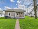 Charming single-story home with a welcoming front porch and lush green lawn, perfect for outdoor relaxation at 1408 W Jackson St, Muncie, IN 47303