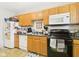 Practical kitchen with wood cabinetry, black appliances, and a durable countertop at 1408 W Jackson St, Muncie, IN 47303