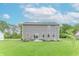 The back exterior of this home offers a patio, lush green grass, and landscaping at 1417 Layton Rd, Anderson, IN 46011