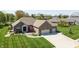 This aerial shows a brick home with an attached 2-car garage, mature trees, and a lush green lawn at 1426 Manchester Dr, Danville, IN 46122