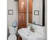 Compact bathroom featuring a classic pedestal sink, decorative mirror, and convenient storage cabinet at 17 W Washington St, Mooresville, IN 46158