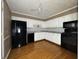 A kitchen with white cabinetry, black appliances, a ceiling fan, and hardwood flooring at 1705 Witt Rd, Lebanon, IN 46052