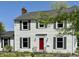 Charming two-story home featuring a bright red front door, white siding, green shutters, and mature landscaping at 2405 Sycamore St, Columbus, IN 47201