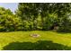 Backyard landscape featuring a rustic fire pit surrounded by green grass and mature trees at 269 Manchester Ct, Noblesville, IN 46060